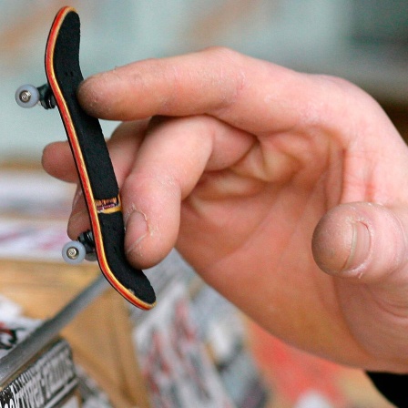 Fingerboarding: eine Hand führt ein winziges Skateboard mit viel Fingerfertigkeit durch eine entsprechend kleine Halfpipe