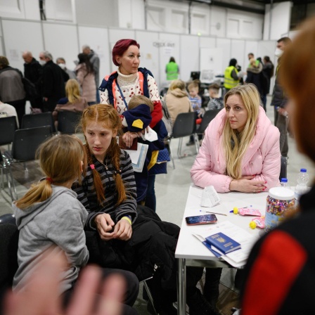 Oksana (r) aus Saporischschja und Lubmila (stehend) aus Odessa warten mit ihren Kindern im Ankunftszentrum Dresden für geflüchtete Menschen aus der Ukraine in der Messe. In dem Ankunftszentrum bekommen die Menschen Informationen, Beratung, medizinische Hilfe und kurzzeitige Übernachtungsmöglichkeiten.