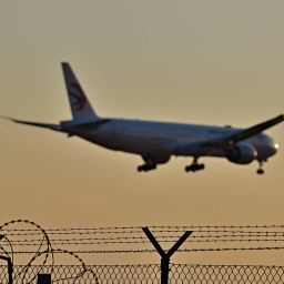 Asyl und Abschottung Stacheldrahtbewehrte Zäune, darüber ein Flugzeug
