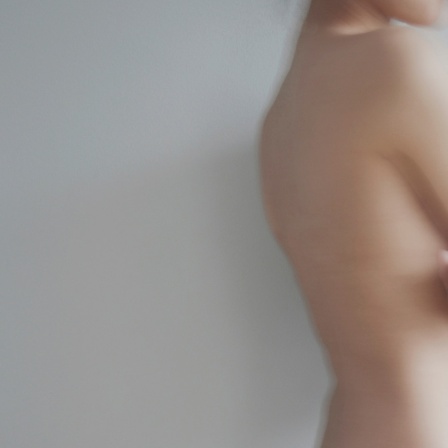Die Silhouette einer nackten Frau mit verschränkten Armen.