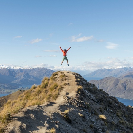 Ein Mann macht einen Luftsprung auf einem Berggipfel