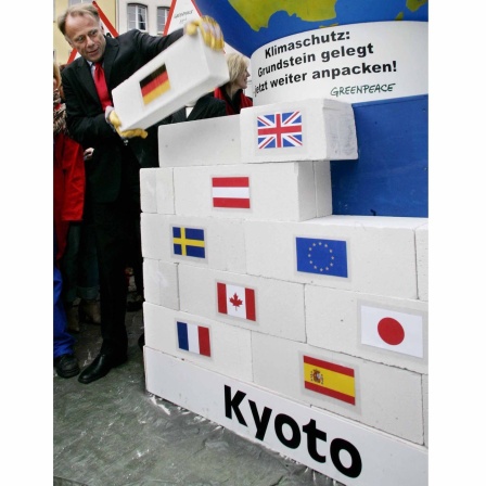 Jürgen Trettin stellt den letzten Stein des symbolischen Fundaments für das Kyoto-Protokoll in die Mauer