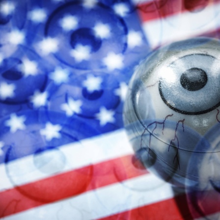Amerikanische Flagge, darauf ein Auge (Grafik): Die USA spielen eine wichtige Rolle bei Verschwörungstheorien. Grund sind der weltweite Einfluss der USA und der amerikanischen Popkultur