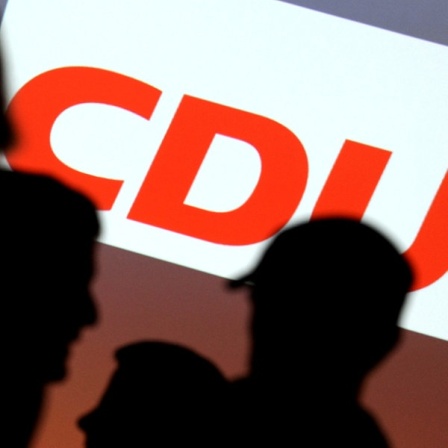 Schattensilhouetten von Wählern vor einem Wahlplakat der CDU.