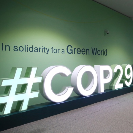 Während der COP29 laufen Menschen an einem COP29-Logo vorbei, Baku, Aserbaidschan.