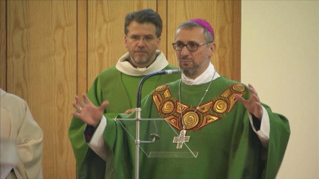 Bischof Stefan Heße steht mit ausgebreiteten Armen an einem Mikrofon