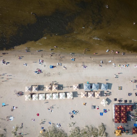 Jumala Beach in der Nühe von Riga an der lettischen Ostseeküste von oben. Am Strand sind einige Menschen und Sonnenschirme zu erkennen.