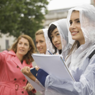 Eine Lehrerin besichtigt mit drei Schülerinnen eine Stadt und erklärt etwas