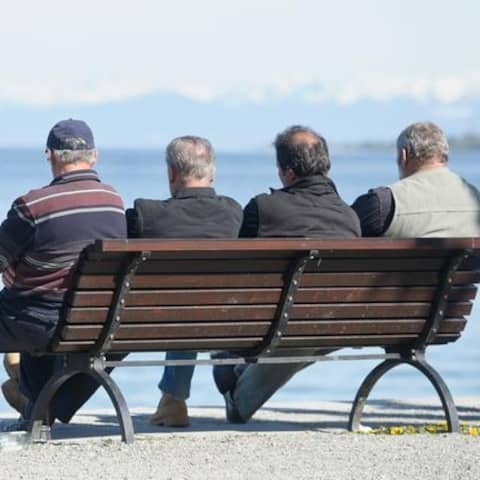 Vier ältere Männer auf einer Bank am See