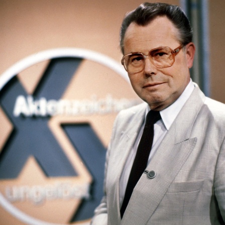 Der Journalist Eduard Zimmermann steht im September 1986 neben dem Logo der von ihm erfundenen, moderierten und produzierten ZDF-Fahndungssendung "Aktenzeichen XY... ungelöst".