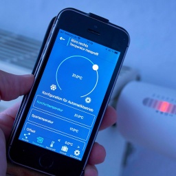 Elektronische Heizungsthermostat wird mit dem Handy eingestellt und zeigt auf dem Display die Wahl zwischen &#034;Komforttemperatur&#034; von 21°C und &#034;Spartemperatur&#034; von 17°C. Zwei Drittel des Endenergieverbrauchs der privaten Haushalte werden für Wärme aufgewendet - also für die Heizung. Hier gibt es also großes Sparpotenzial.