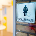 Ein Schild "Schülerinnen" hängt an einer Schultoilette eines Gymnasiums