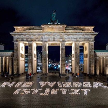 Ein großer Schriftzug "Nie wieder ist jetzt" aus tausenden Kerzen-Lichtern vor dem Brandenburger Tor.