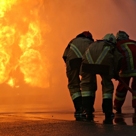 Mehrere Feuerwehrleute löschen einen Brand. 
