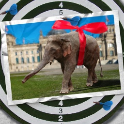 Eine Fotomontage zeigt eine Elefanten mit einer roten Schleife um den Körper vor dem Reichstags Gebäude in Berlin.