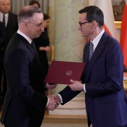 Andrzej Duda (l), Präsident von Polen, gibt Mateusz Morawiecki, Ministerpräsident von Polen, während einer Vereidigungszeremonie die Hand. Duda hat das neue Kabinett des bisherigen nationalkonservativen Ministerpräsidenten Morawiecki vereidigt.