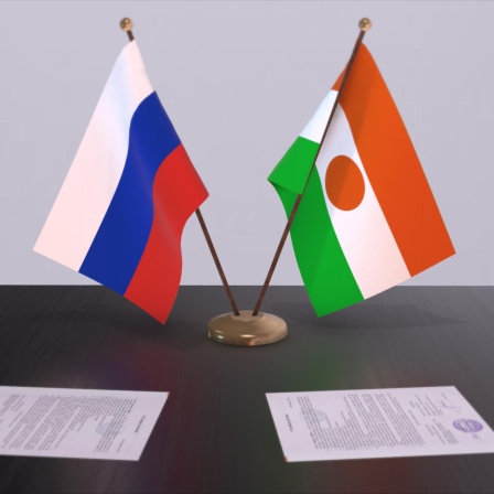 Die Nationalflaggen Russlands und Nigers stehen auf einem Tisch nebeneinander. 