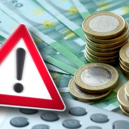 Bildmontage: Ein Achtung-Schild vor Euroscheinen und Münzen.