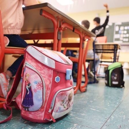 Schulranzen stehen in einer Grundschule neben der Bank. 