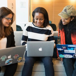 Drei Frauen fröhlich an ihren Laptops