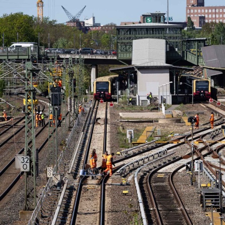 Bauarbeiter gehen über Bahngleise am S-Bahnhof Westend. Nach dem Abriss der Ringbahn- und der Westendbrücke soll die Ringbahn ab Montag wieder fahren.