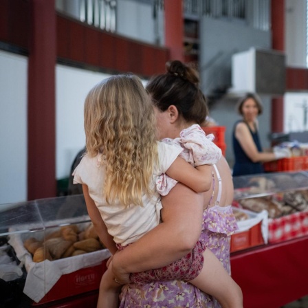 Eine Mutter mit ihrem Kind auf dem Arm von hinten. Bei der Berliner Tafel. 