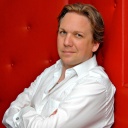 Kabarettist Matthias Brodowy sitzt auf einer roten Couch