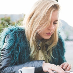 Junge Frau in Lederjacke, sitzt in einem Cafe und benutzt ein Tablet