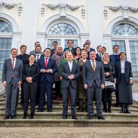 Bundeskanzler Olaf Scholz (SPD), steht beim Familienfoto bei der Klausurtagung des Bundeskabinetts auf Schloß Meseberg. 