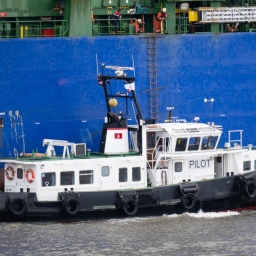 Ein Lotsenboot leigt längsseits eines großen Containerschiffs im Hamburger Hafen.