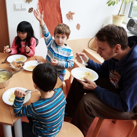 Vorschulkinder und ihr Erzieher beim Mittagessen in der Kita