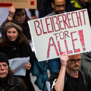 Abschiebe-Gegner demonstrieren mit Plakaten auf dem Frankfurter Flughafen.