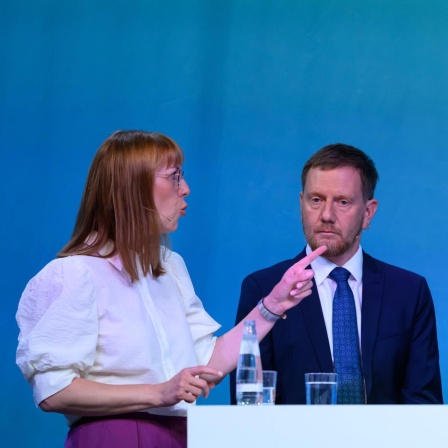 Katja Meier (Bündnis90/Die Grünen, l-r), Justizministerin von Sachsen,Michael Kretschmer (CDU), Ministerpräsident von Sachsen und Jörg Urban, Vorsitzender der AfD in Sachsen, stehen an einem Tisch und diskutieren miteinander.