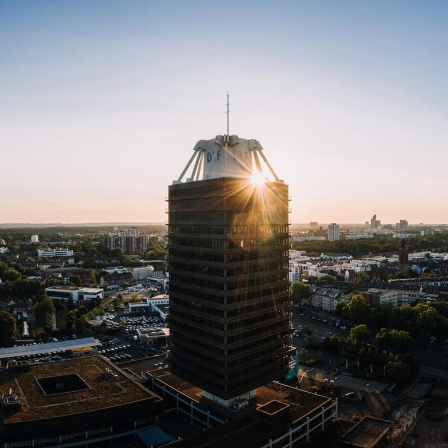 Das Hochhaus des Deutschlandfunks in einer Luftaufnahme mit untergehender Sonne im Hintergrund.