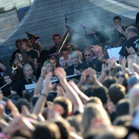 Wacken Festival: Zuschauer:innen vor einer Bühne, auf der eine Kapelle spielt.