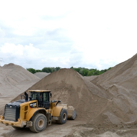 Das Beitragsbild des Dok 5 Feature "Auf Sand gebaut - Konlikt um Sand und Kies", zeigt ein Kieswerk mit Bagger und Förderturm