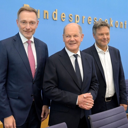 Christian Lindner, Olaf Scholz und Robert Habeck lächeln auf der Pressekonferenz in die Kameras