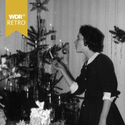 Eine Frau zündet die Kerzen am Weihnachtsbaum an