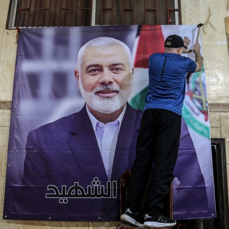 Ein Palästinenser hängt ein großes Bild von Ismail Hanija in einer Halle im palästinensischen Flüchtlingslager Burj al-Brajneh auf.