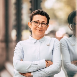 Britta Selle steht angelehnt an einer Glasfront.