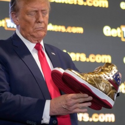 Der republikanische Präsidentschaftskandidat Donald Trump hält goldene Trump-Sneakers auf der
Sneaker Con Philadelphia in Händen.