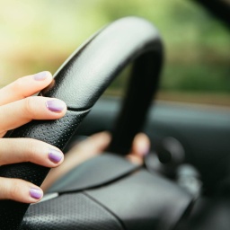 Sports car steering wheel, woman is driving