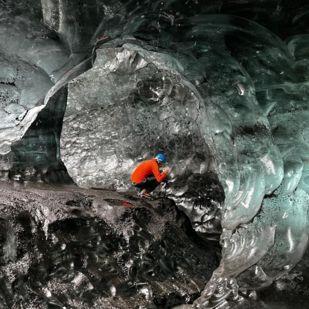 Ein Bergsteiger sitzt in einer Eishöhle