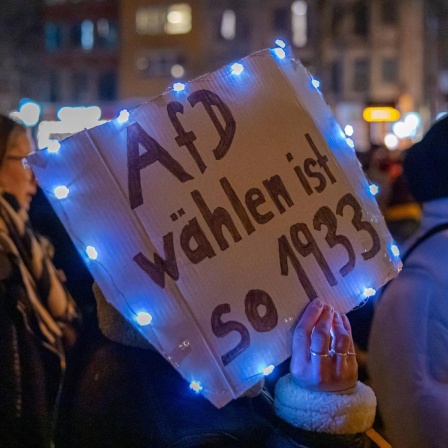Bei der Demonstration gegen Rechts in Köln hält eine Demonstrantin ein Schild mit der Aufschrift "AfD wählen ist so 1933" in die Luft