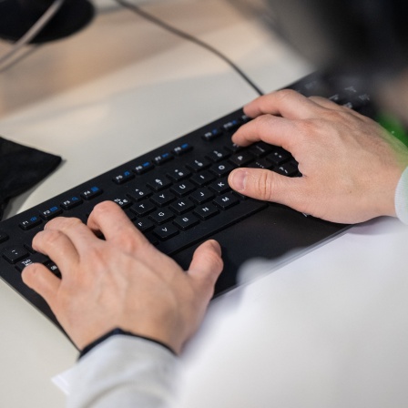Hände arbeiten auf einer schwarzen Tastatur