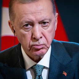 Porträt des türkischen Präsodenten Erdogan, der grimmig in die Kamera guckt. Im Hintergrund sind Teile der türkischen Flagge zu erkennen.