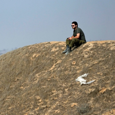 Ein israelischer Soldat sitzt auf einer Anhöhe nahe der Grenze zum Gazastreifen im Süden Israels.