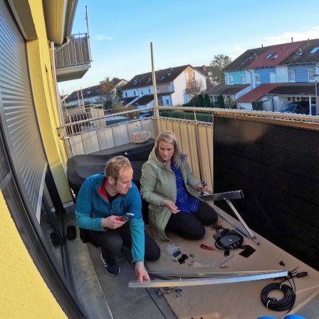 Eine Frau und ein Mann beim Aufbau eines Balkonkraftwerks