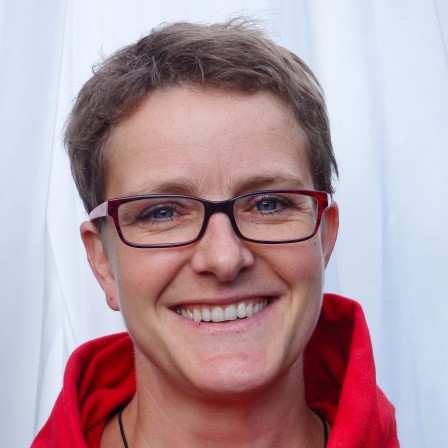 Eine Frau mit Brille und kurzem Haar lächelt in die Kamera.