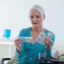 Eine Frau mittleren Alters liest den Beipackzettel einer Schachtel Tabletten: Nach wie vor lehnen viele Frauen, die unter den Wechseljahren leiden, eine Hormonersatztherapie ab. Doch der Nutzen bei Beschwerden liegt über den Risiken.